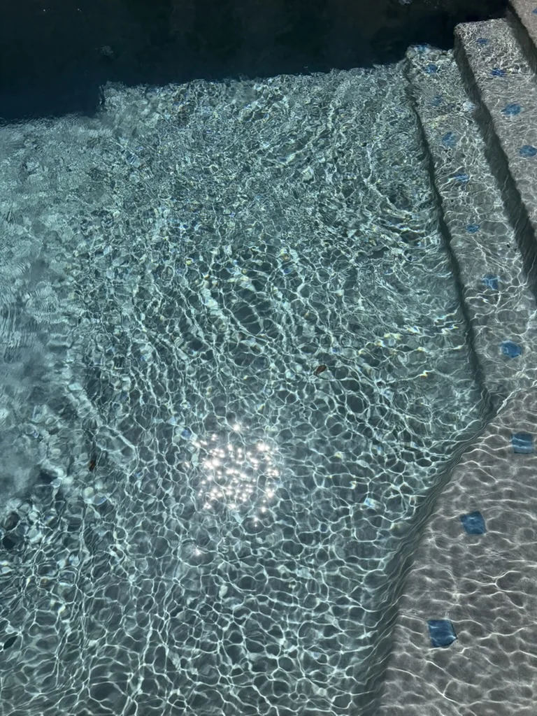 Clear water and sunlight over tiled pool steps.